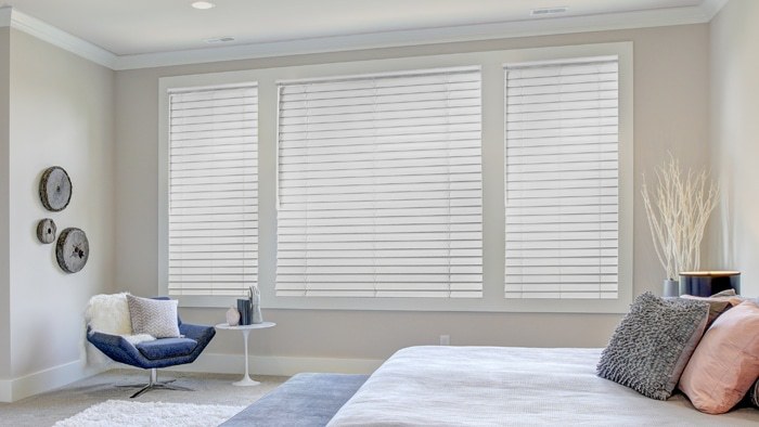 White blinds in a bedroom with a blue accent chair