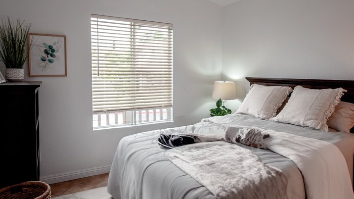 White blinds in a bedroom with a dark wood headboard