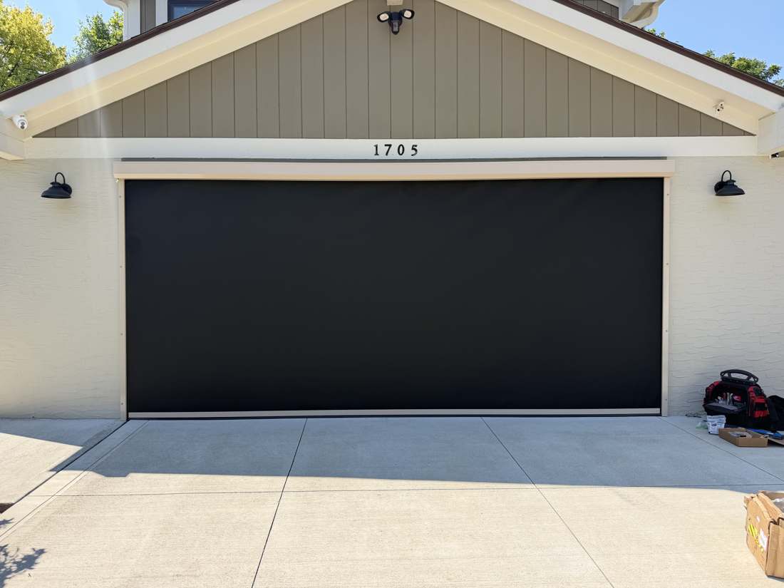 Exterior motorized screen covering a garage opening