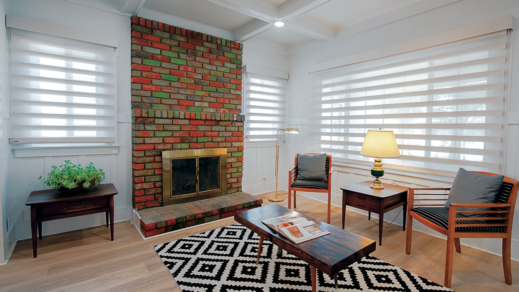 Sheer roman shades in a living room with a brick fireplace
