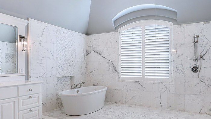 White shutters in an arched bathroom window