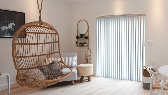 Light blue vertical blinds behind a boho hanging chair