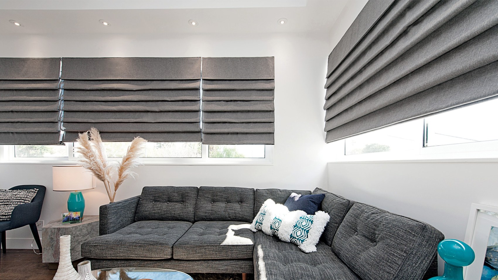 Gray roman shades in a cozy living room with a sectional sofa