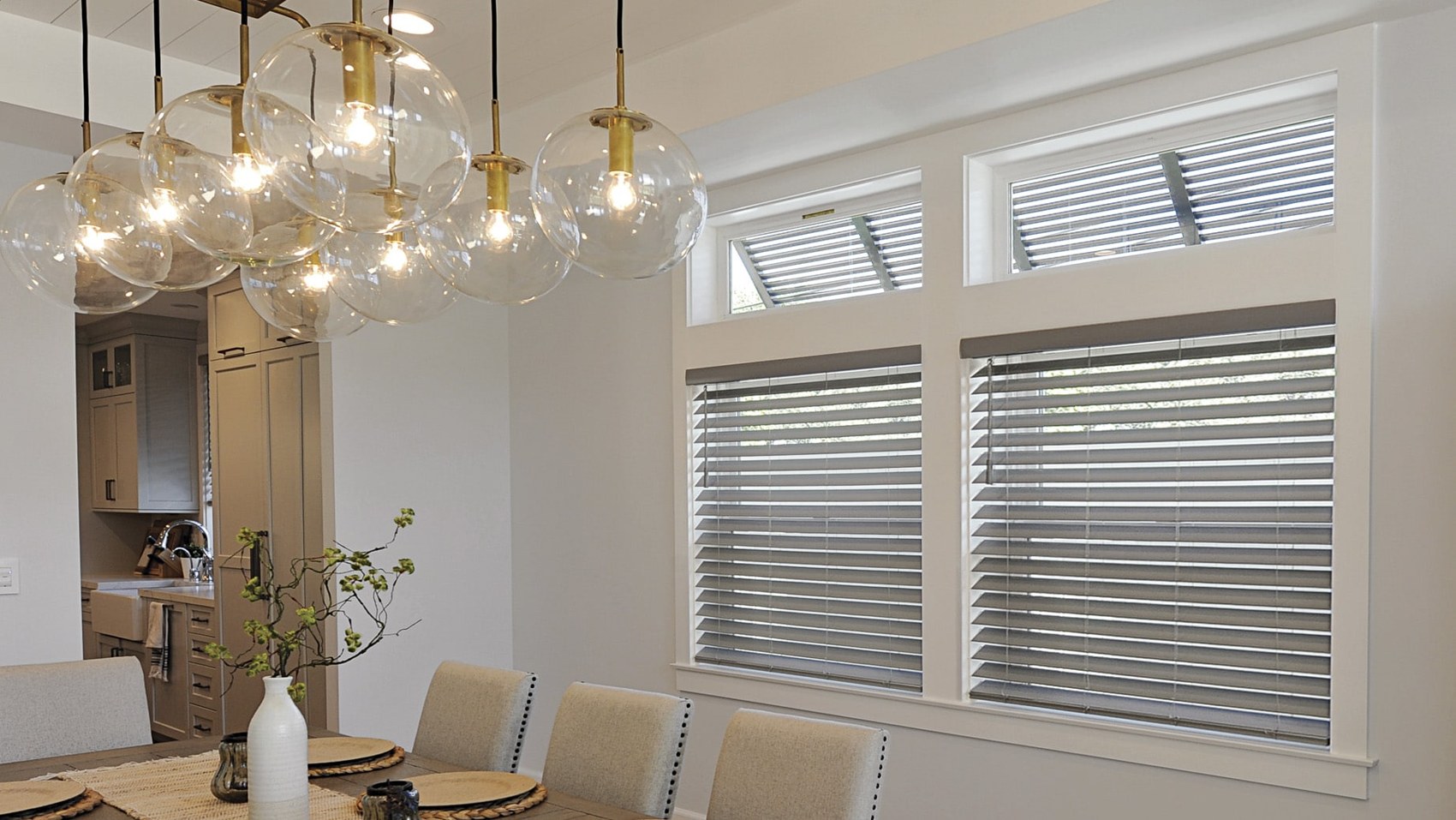 Aluminum blinds in a dining room with glass globe pendants