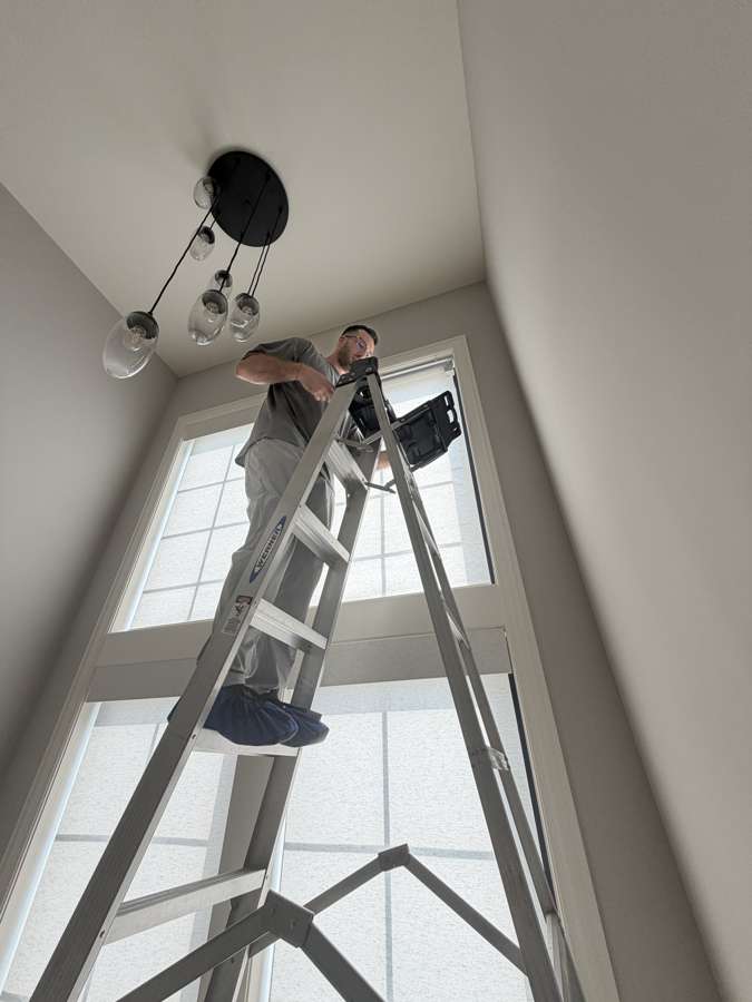 Installer servicing shades on a tall window
