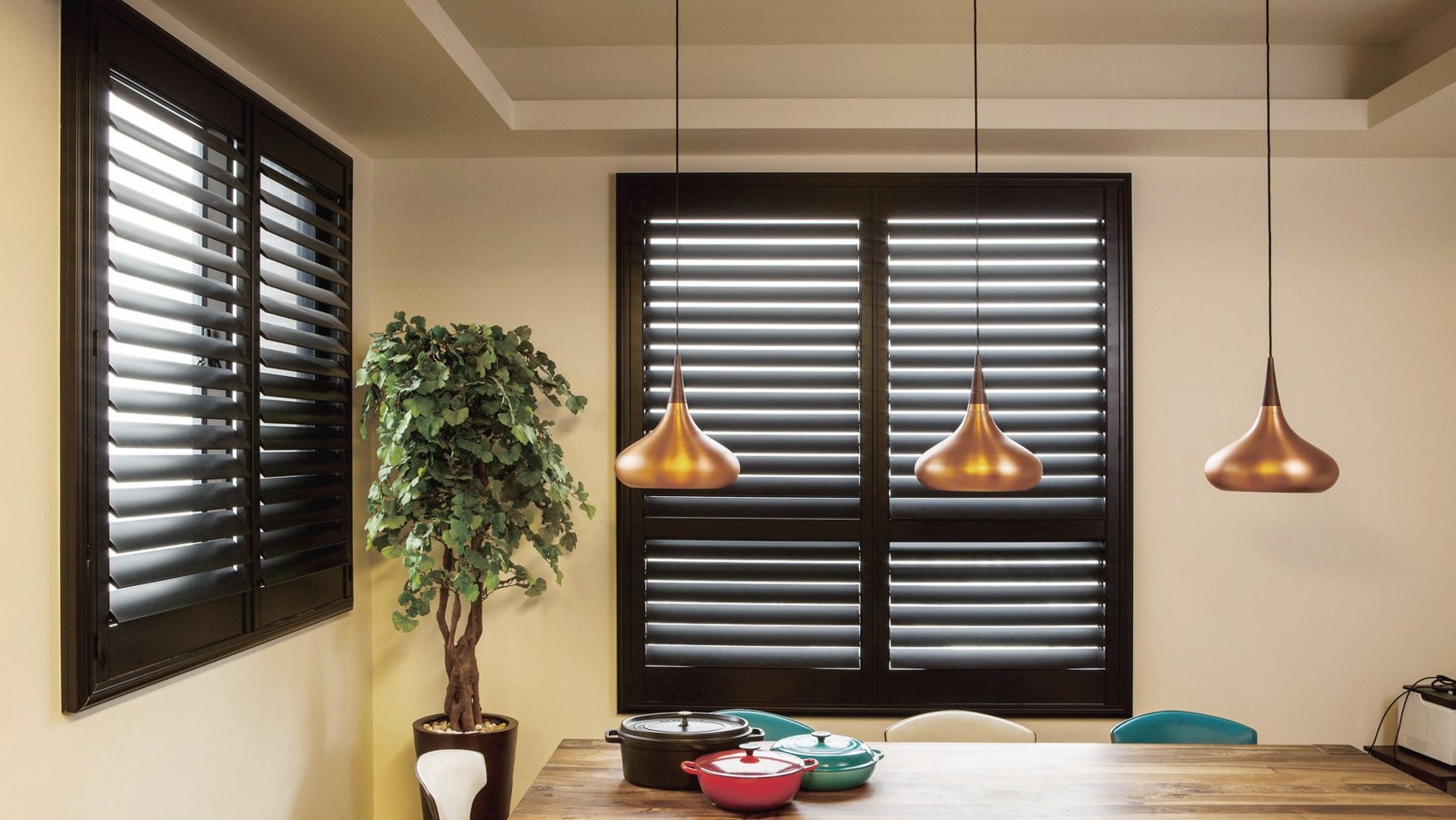 Espresso-stained shutters in a dining room with copper pendants